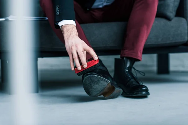 Partial view of businessman cleaning stylish black shoes — Stock Photo