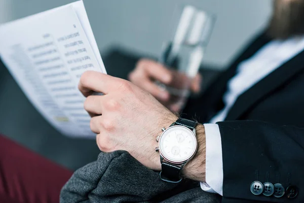 Recortado tiro de hombre de negocios con vaso de agua y periódico - foto de stock