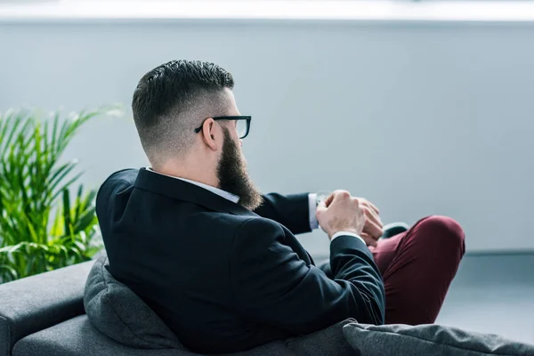 Partial view of bearded businessman in eyeglasses checking time — Stock Photo