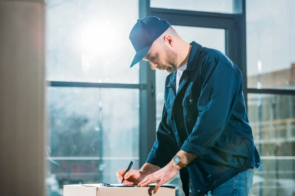 Courier checking cardboard box and cargo declaration — Stock Photo