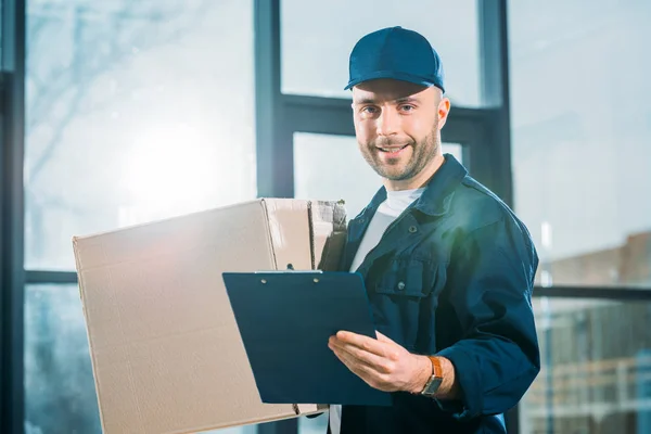 Courier holding cardboard box and cargo declaration — Stock Photo