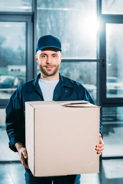 Jeune courrier tenant boîte en carton — Photo de stock