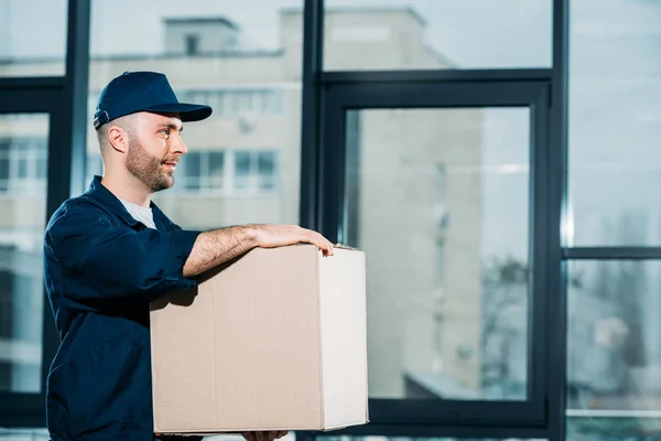 Jeune livreur portant une boîte en carton — Photo de stock