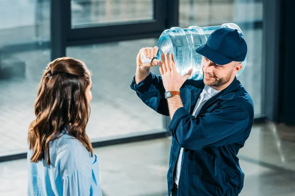 Femme regardant livreur tenant bouteille d'eau — Photo de stock