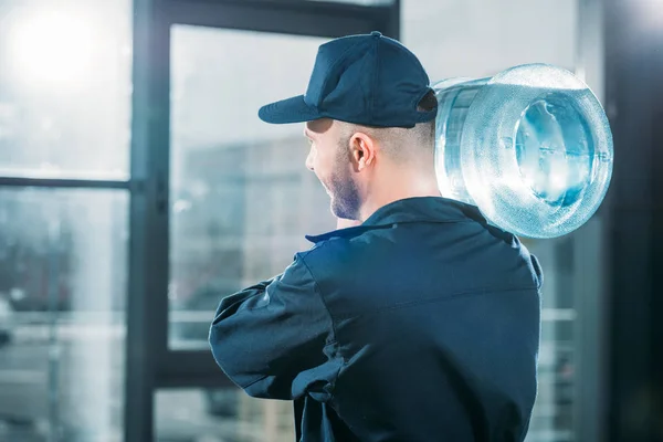 Vista trasera del cargador que lleva la botella de agua en el hombro - foto de stock