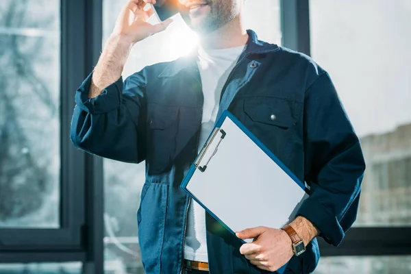Close-up view of courier holding clipboard and talking on a phone — Stock Photo