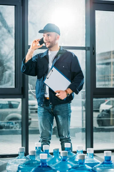 Delivery man with clipboard talking on a phone — Stock Photo