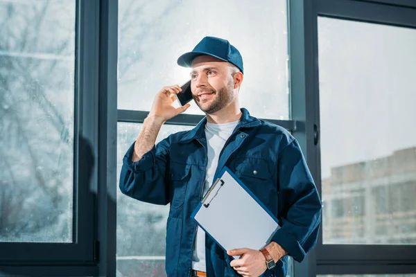 Courier holding clipboard and making a phone call — Stock Photo