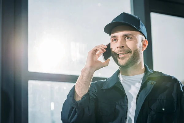 Mensajero sonriente haciendo una llamada telefónica - foto de stock