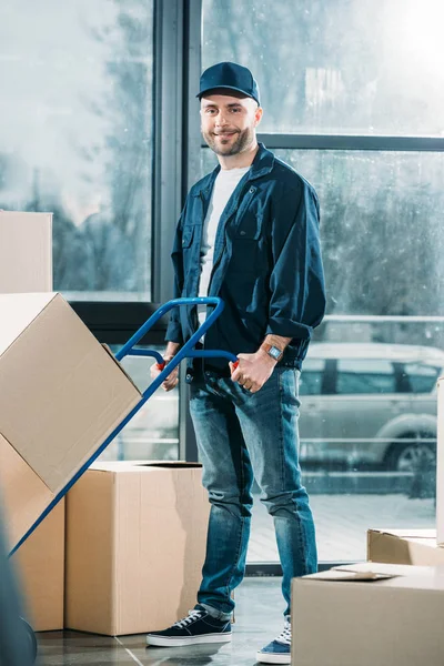 Uomo di consegna spingendo camion a mano con scatole — Foto stock