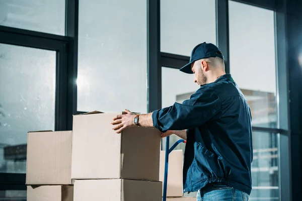 Courier stacking cardboard boxes on handcart — Stock Photo