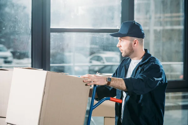 Carregador homem ajustando caixas de papelão no carrinho — Fotografia de Stock