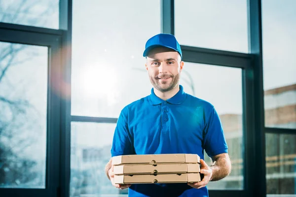 Repartidor sonriente llevando pizzas en cajas — Stock Photo