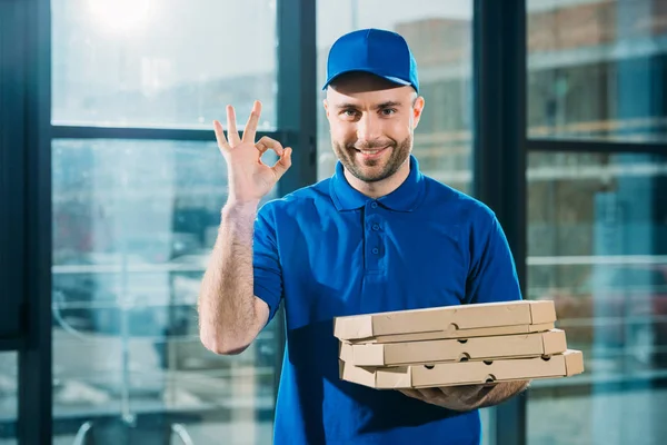 Mensajero sonriente con pizzas en cajas que muestran signo de ok — Stock Photo