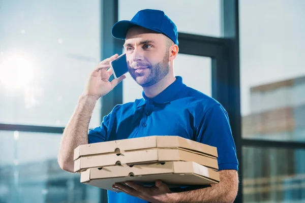 Mensajero con pizzas en cajas haciendo llamada telefónica - foto de stock