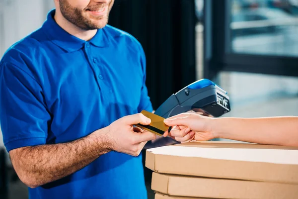 Woman holding stack of pizzas in boxes and passing card for carrier with payment terminal — Stock Photo