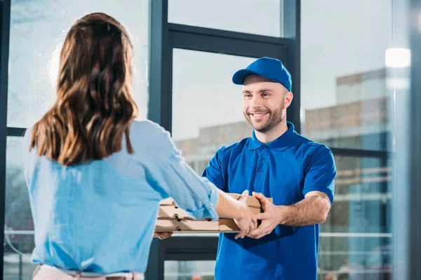 Mensajero dando mujer pila de pizzas en cajas - foto de stock