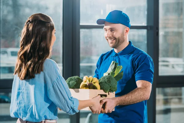 Mensajero dando caja de mujer con frutas y verduras frescas - foto de stock