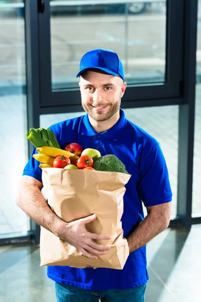 Entrega homem segurando saco de papel com frutas e legumes frescos — Fotografia de Stock