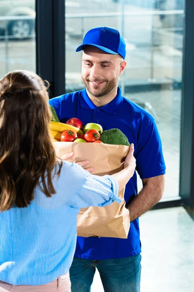 Woman receiving groceries in bag from courier — Stock Photo
