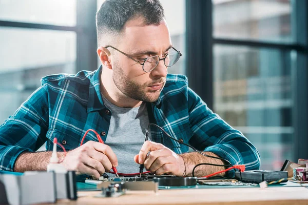 Werkstattmitarbeiter testen Leiterplatte und prüfen Multimeter-Messungen — Stockfoto