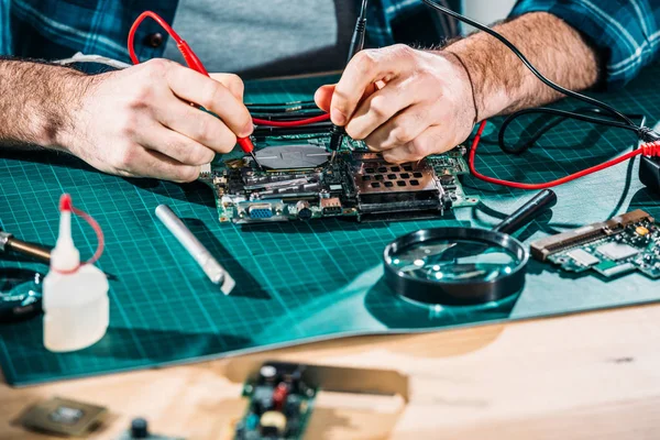 Vista de cerca del ingeniero masculino que trabaja con placa de circuito y multímetro — Stock Photo