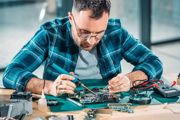 Hardware engineer in glasses soldering pc parts — Stock Photo