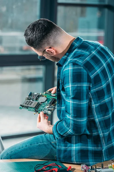 Rear view of engineer looking at circuit board — Stock Photo