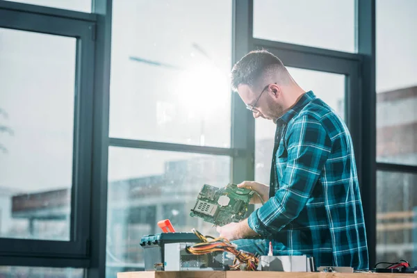 Homme ingénieur regardant la carte de circuit imprimé — Photo de stock