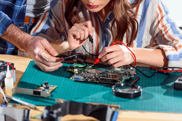 Team of engineers working with circuit board and multimeter — Stock Photo