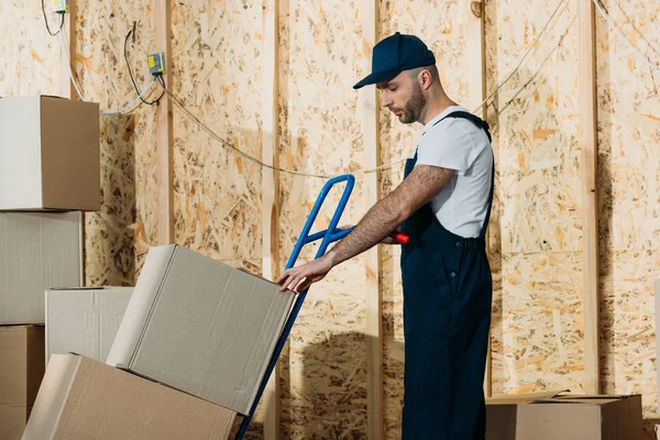 Loader man adjusting cardboard boxes on delivery cart — Stock Photo