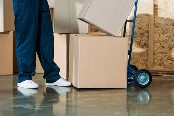 Mensajero apilando cajas de cartón en el carrito de mano - foto de stock