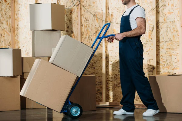 Delivery man carrying boxes on hand truck — Stock Photo