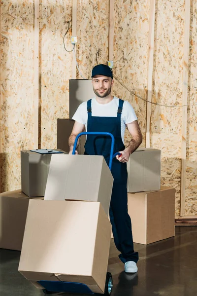 Uomo di consegna che trasporta scatole sul carrello — Foto stock