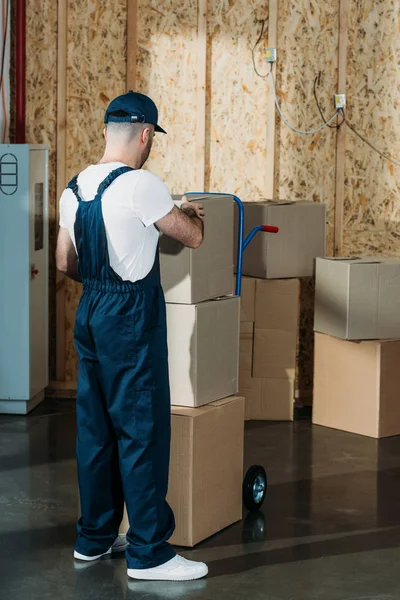 Loader man adjusting cardboard boxes on cart — Stock Photo