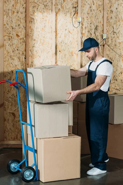 Cargador hombre apilar cajas de cartón en el carrito - foto de stock
