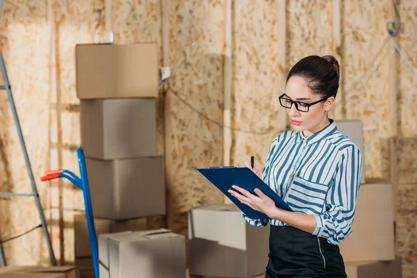 Jeune femme d'affaires inspectant les documents de livraison — Photo de stock