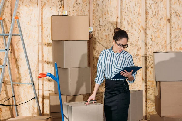 Femme d'affaires avec presse-papiers vérifiant les colis de livraison — Photo de stock