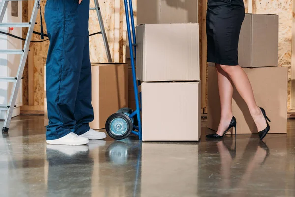 Businesswoman and delivery man standing by stack of cardboard boxes — Stock Photo
