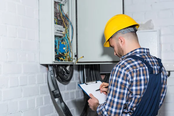 Eletricista profissional inspecionando fios em caixa elétrica — Fotografia de Stock