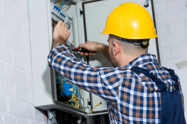 Électricien mâle vérifiant les fils dans la boîte électrique — Photo de stock