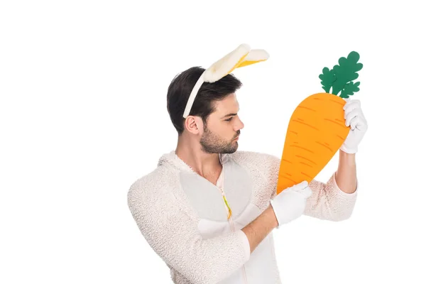 Hombre vistiendo traje de conejo y sosteniendo zanahoria aislado en blanco, concepto de Pascua - foto de stock