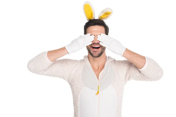 Homme souriant en costume de lapin fermant les yeux par des mains isolées sur blanc, concept de Pâques — Photo de stock