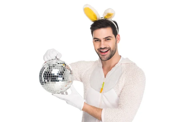 Sorrindo homem em traje de coelho segurando bola de discoteca isolado no branco, conceito de Páscoa — Fotografia de Stock