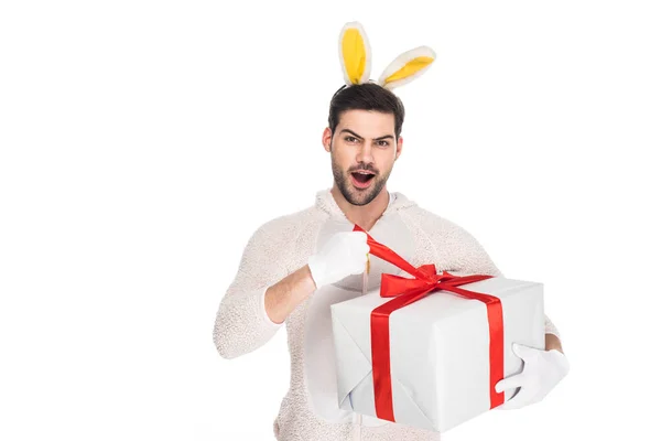 Hombre en traje de conejo quitando la cinta de la caja de regalo aislado en blanco, concepto de Pascua - foto de stock