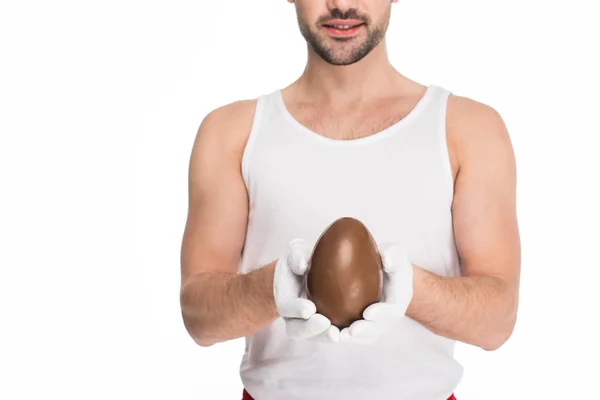 Молодий чоловік тримає велике шоколадне яйце в руках ізольовано на білому, Великодньому концепті — стокове фото