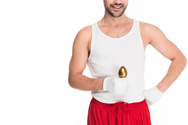 Обрізаний вид усміхненого чоловіка, що тримає золоте яйце ізольовано на білому, Великодньому концепті — стокове фото