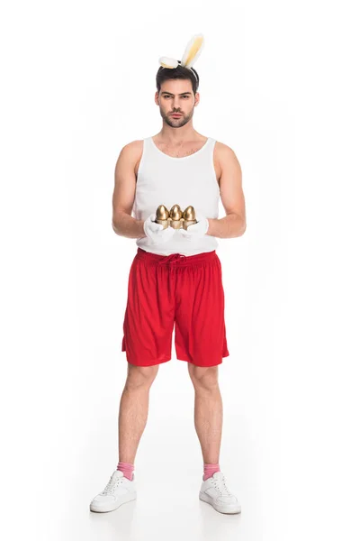 Homme aux oreilles de lapin tenant des œufs d'or isolés sur blanc, concept de Pâques — Photo de stock