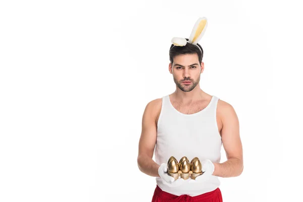 Чоловік з вухами кролика тримає золоті яйця ізольовані на білому, Великодньому концепті — стокове фото