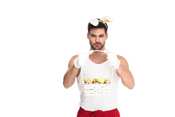 Jeune homme avec des oreilles de lapin tenant panier de fruits isolés sur blanc, concept de Pâques — Photo de stock